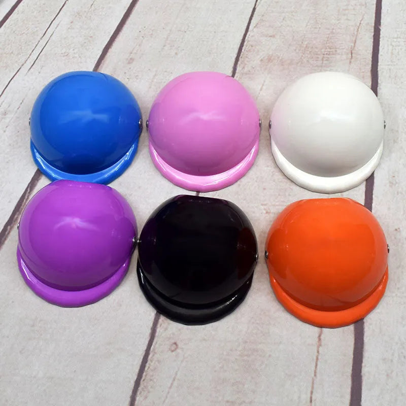 A pink plastic motorcycle cap helmet for a dog, shown alongside white, black, and yellow colour options.