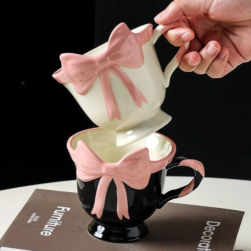 Ceramic mug with a pink and white girl's heart bow decoration on the side.