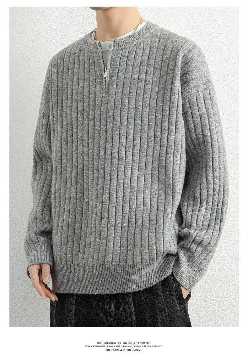 Man wearing a grey half-zip loose knit sweater, showing the textured fabric and front zip.
