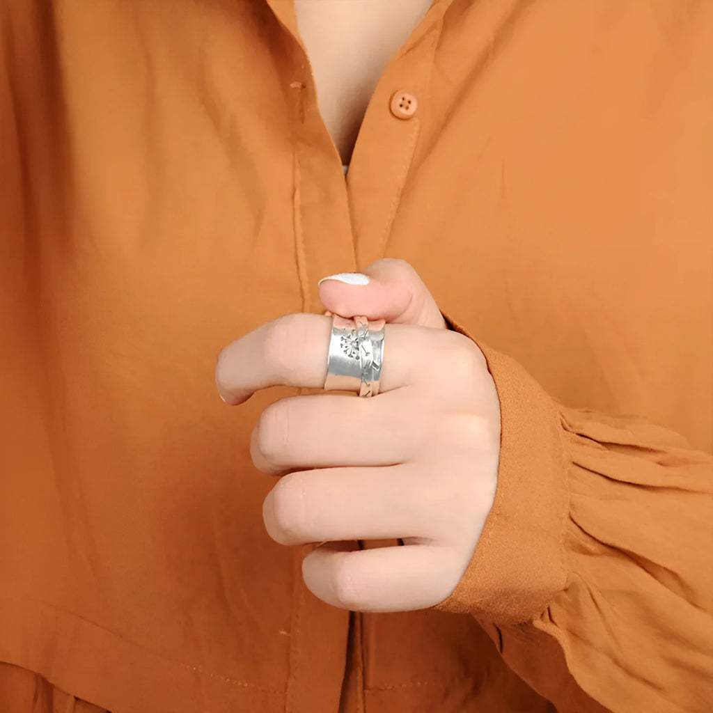 Silver rotatable flower ring on a finger showing the floral design.