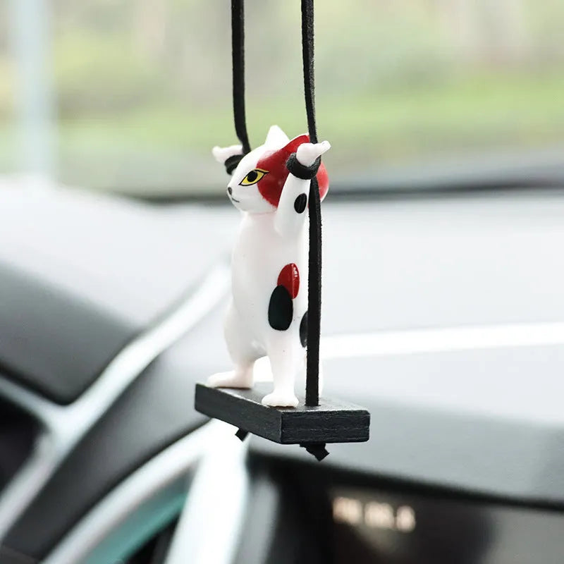 Cartoon style resin cat pendant on a rope for hanging in a car, shown in multiple colour options.