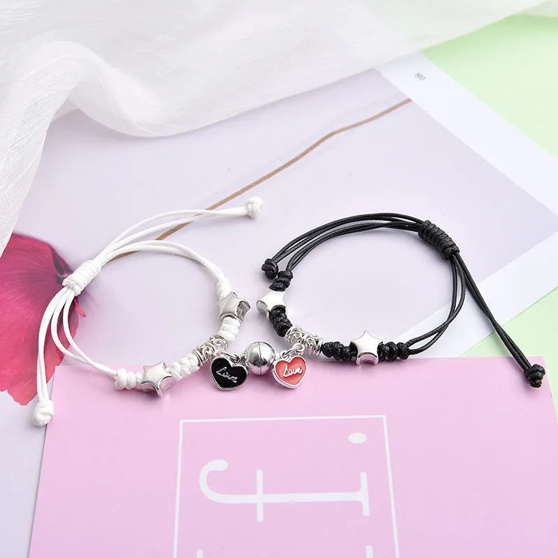 Pair of magnet couple bracelets with suction clasp on wrist, showing alloy designs like crown and love lock.