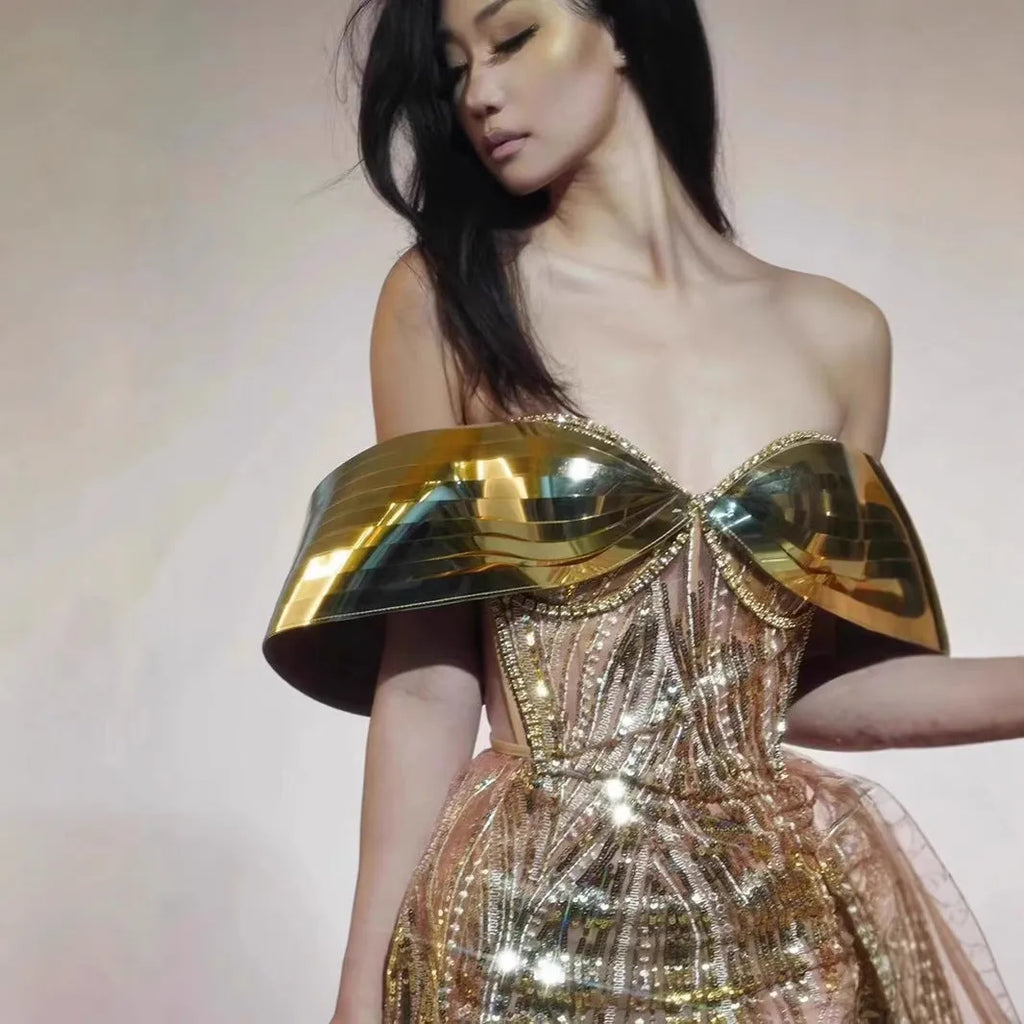 Gold sequined strapless long evening dress with a high split on the skirt, shown on a model.