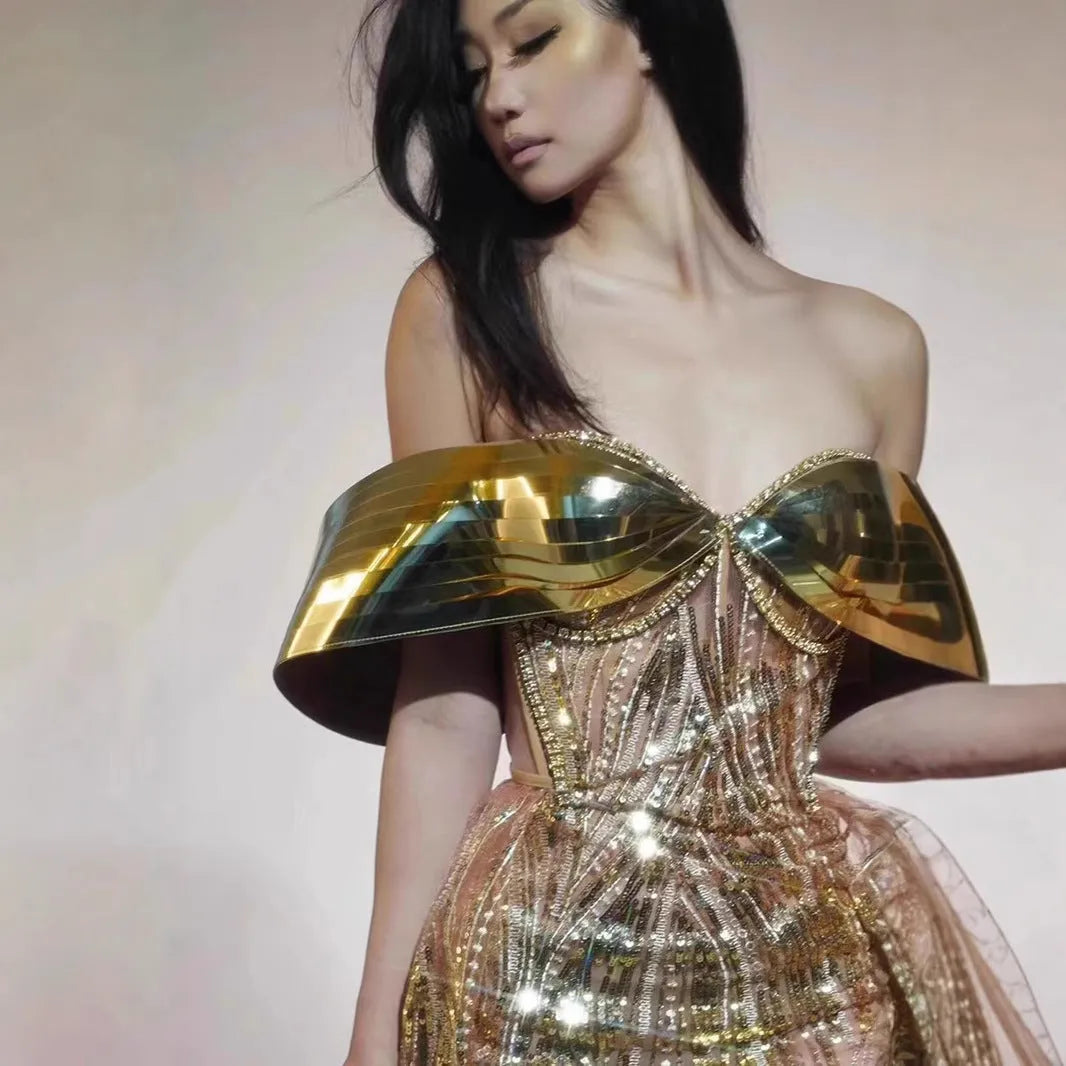 Gold sequined strapless long evening dress with a high split on the skirt, shown on a model.