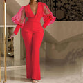 A woman wearing a red wide-leg jumpsuit with long sleeves and an elasticated waist.