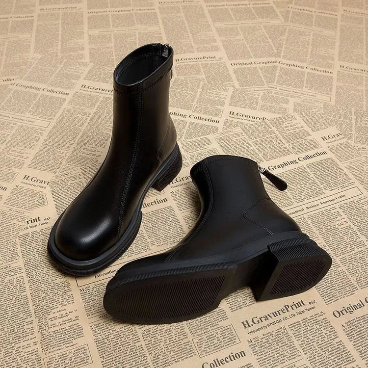 Women's black ankle boots with a flat heel, round toe, and a back zip fastening on a rubber sole.