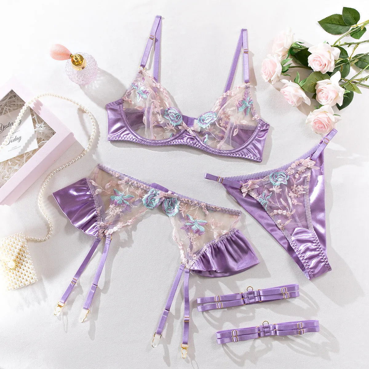 Light purple satin lingerie four-piece set with white embroidery detailing on a mannequin