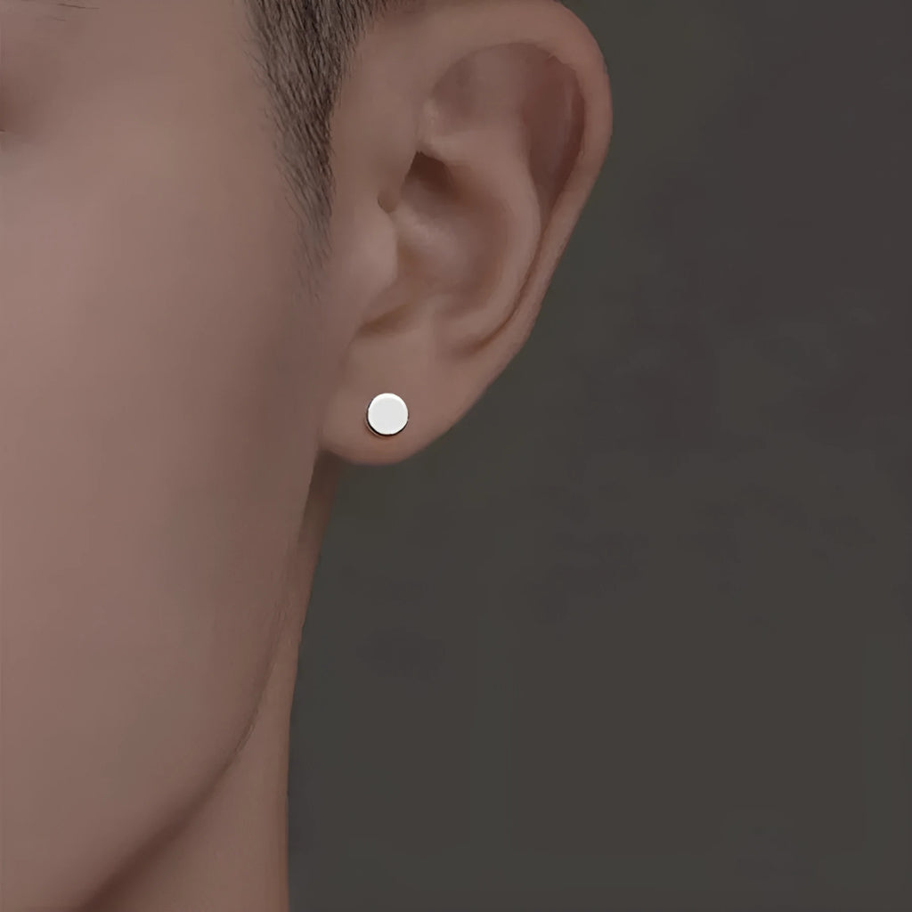 A pair of simple, round, flat-fronted S999 sterling silver ear bone studs on a plain background.