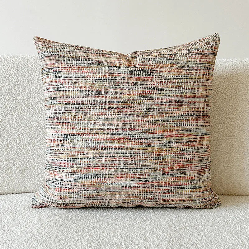 Amber coloured jacquard pillow cover with paisley and floral pattern, shown on a sofa.
