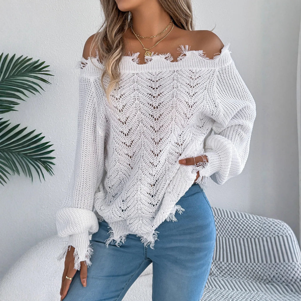 A woman wearing a white hollow-out cut off-the-shoulder pullover sweater in a street fashion style.