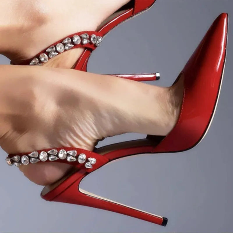 Women's black patent leather pointed toe stiletto sandals with rhinestone decorations along the side.