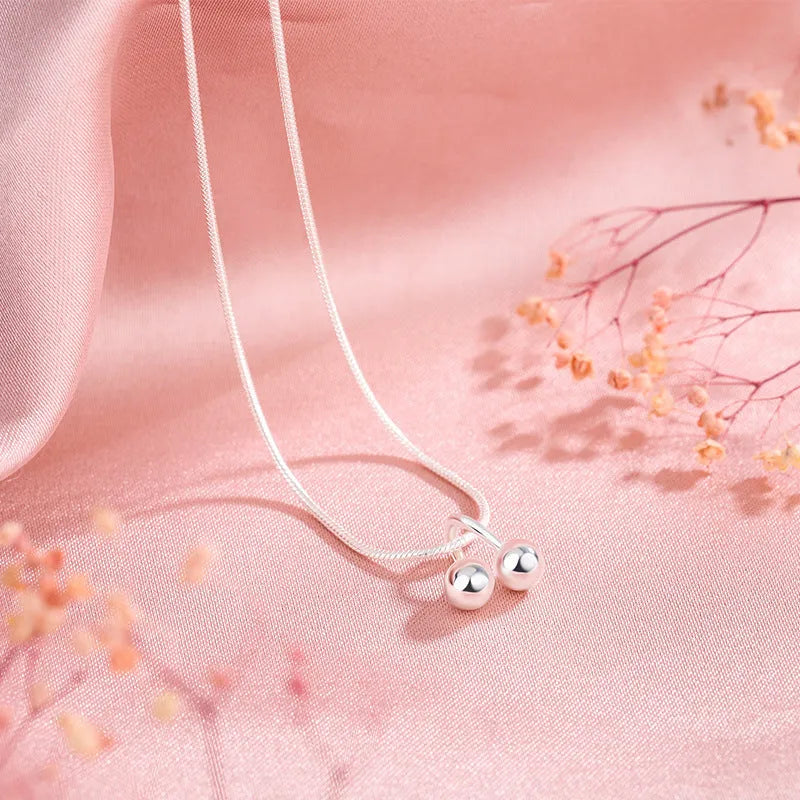 Silver cherry pendant necklace on an adjustable snake bones chain for women.