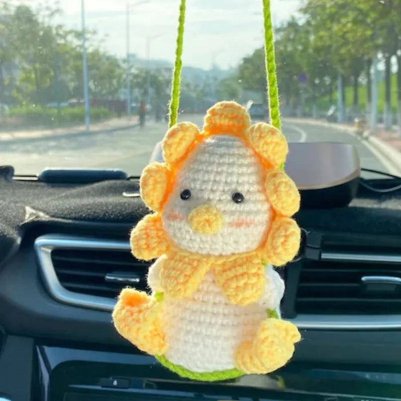Green and white knitted wool car plant decoration with white hanging rope.