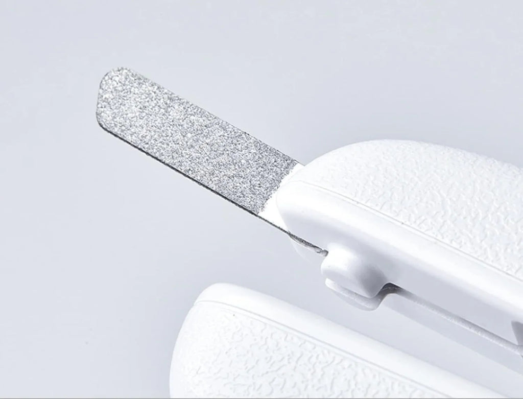 White pet nail clippers with LED light, open transparent splash guard, and separate nail file on a table