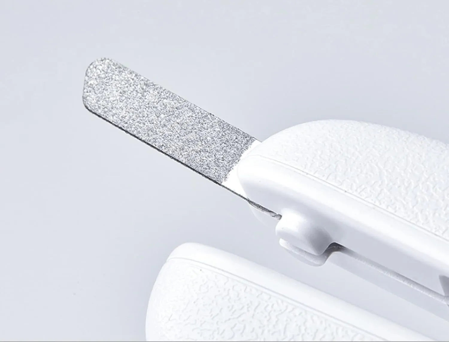 White pet nail clippers with LED light, open transparent splash guard, and separate nail file on a table