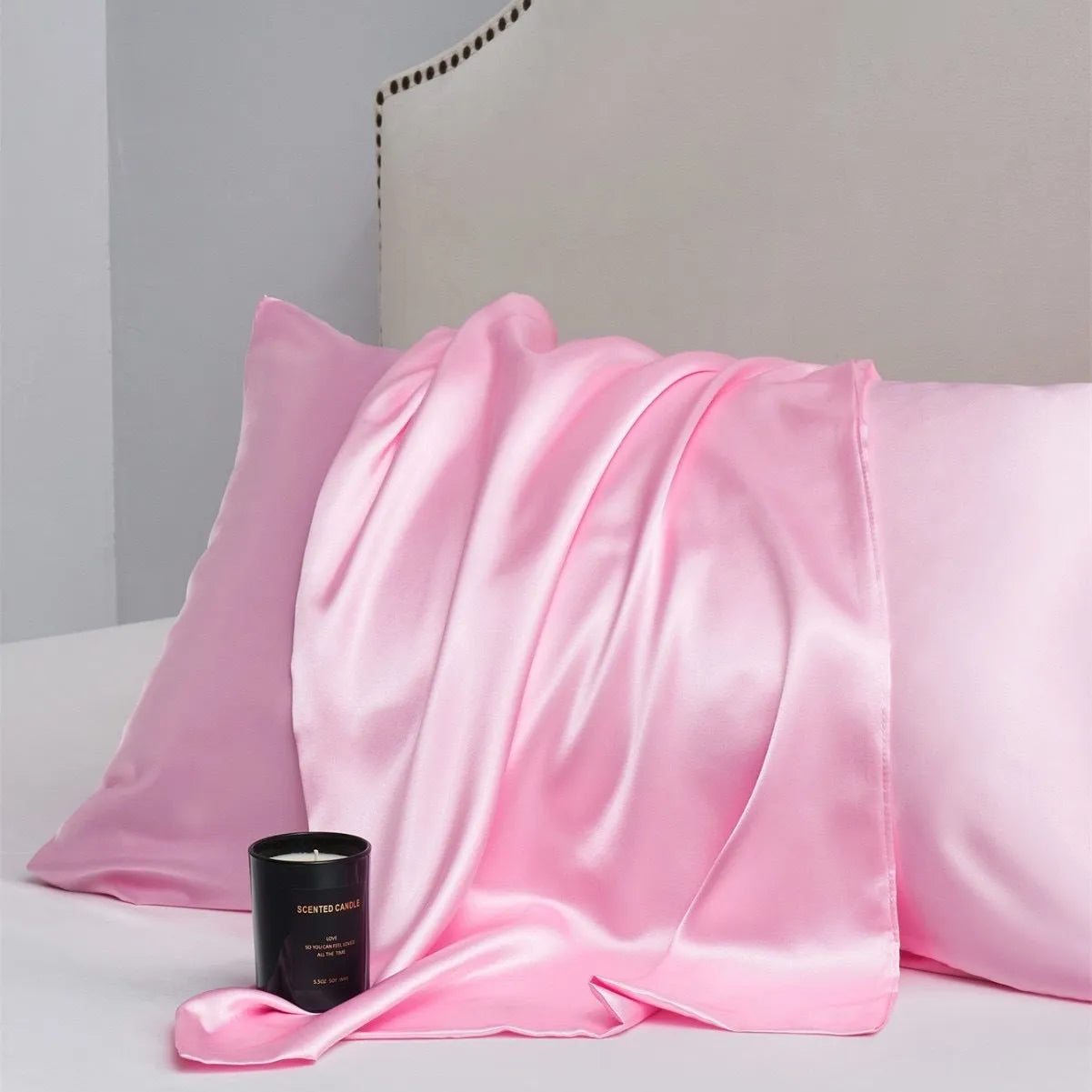 Pair of solid colour satin pillowcases in polyester fabric on a bed.