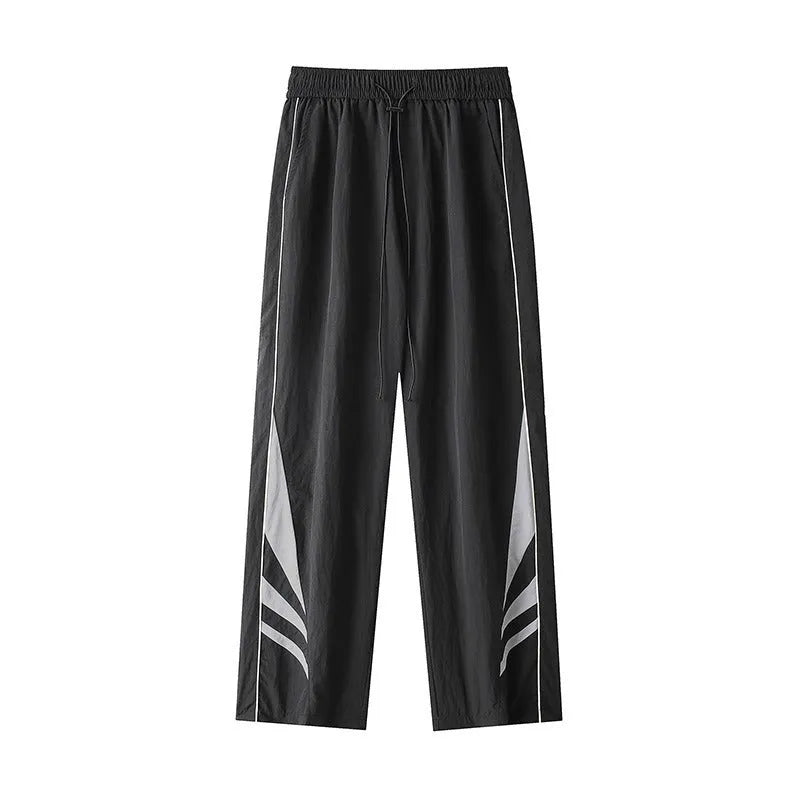 Men's black straight leg loose fit summer sports trousers with an elastic waist on a grey background.
