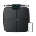 Black eight-electrode body fat smart scale on floor, showing tempered glass platform and stainless steel electrodes.