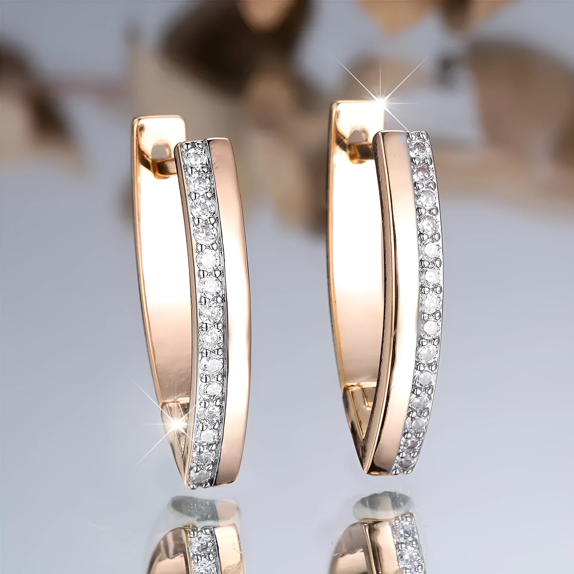 Women's geometric drop earrings with champagne gold electroplating and white diamond accents, showing V-shaped design and clip-on back.