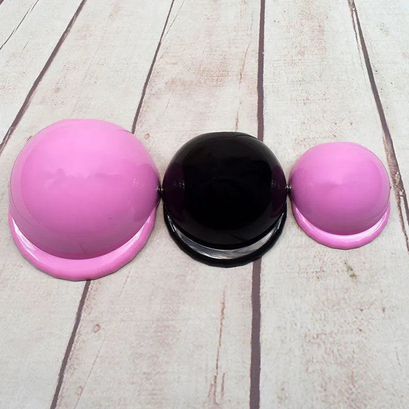 A pink plastic motorcycle cap helmet for a dog, shown alongside white, black, and yellow colour options.