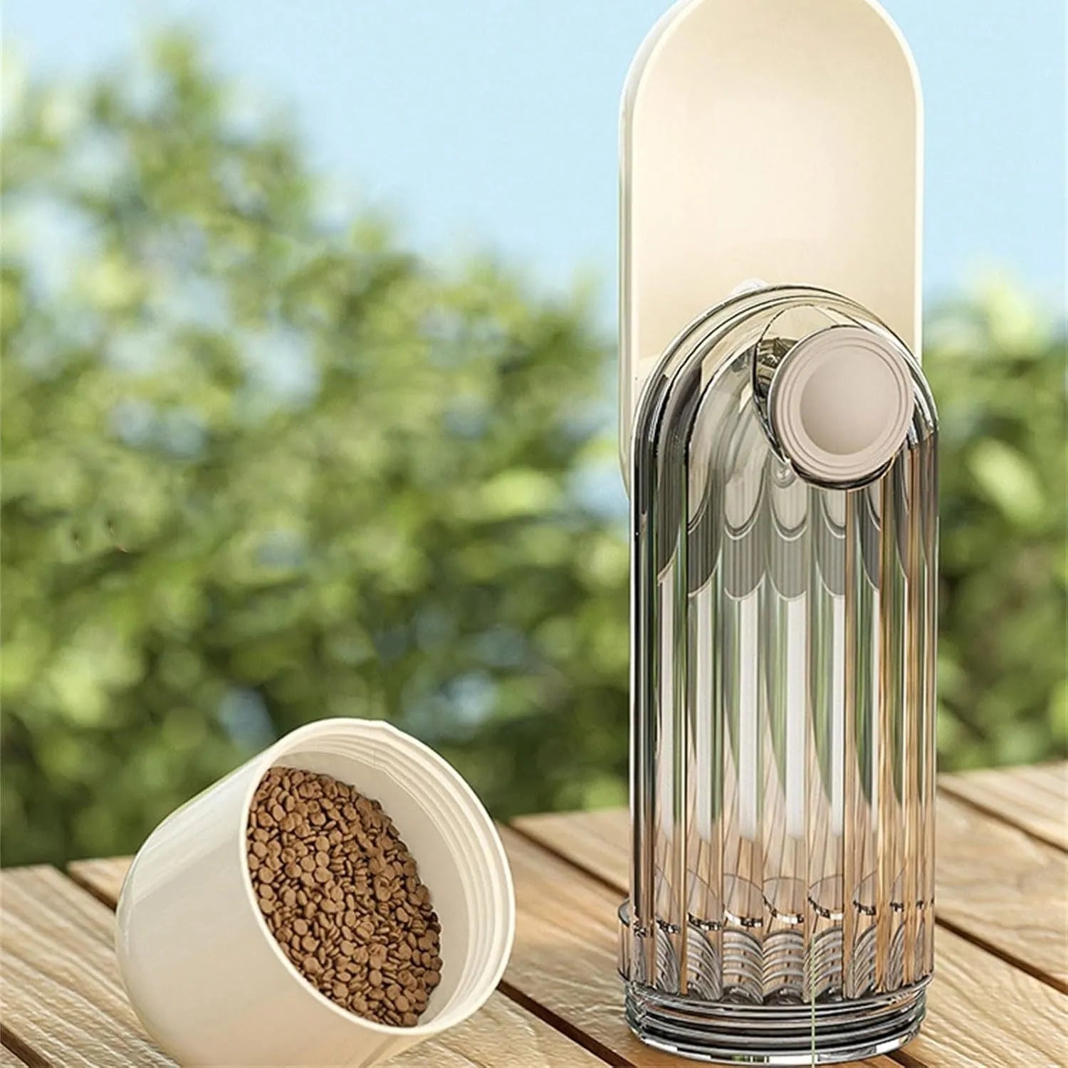 Beige foldable dog water bottle and food dispenser with tray, shown next to a dog on a walk.
