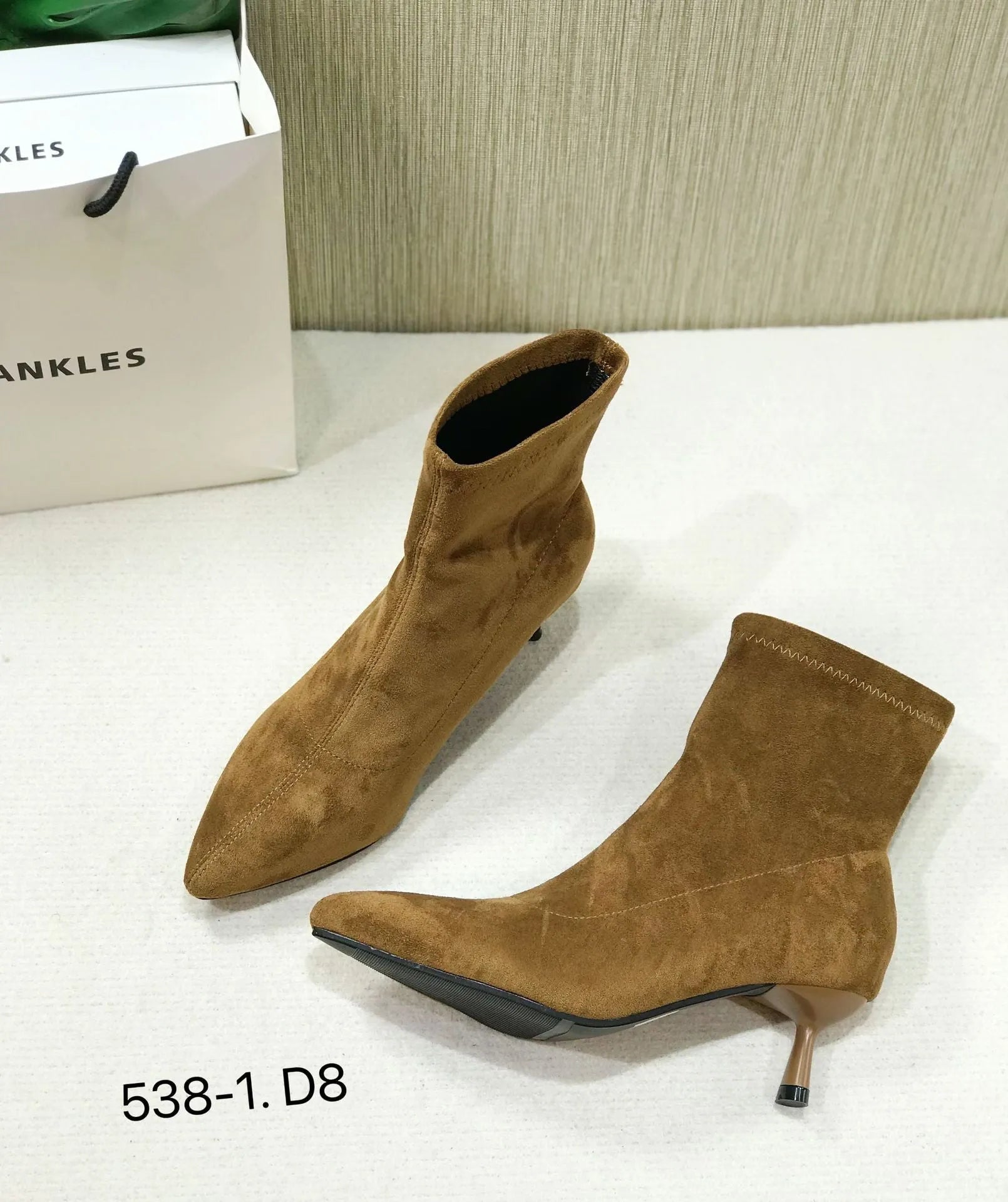 Black pointed toe ankle boots with a stiletto heel on a plain background.