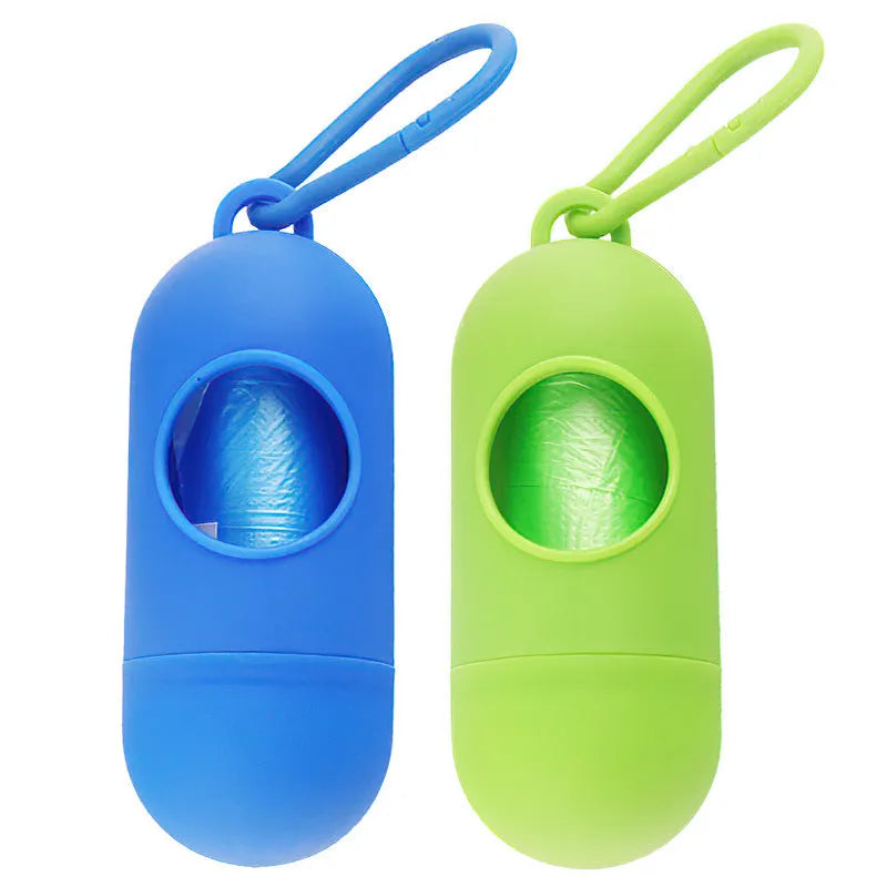 A small black plastic dog poop bag holder with a hook and Velcro strap, shown next to a roll of bags.