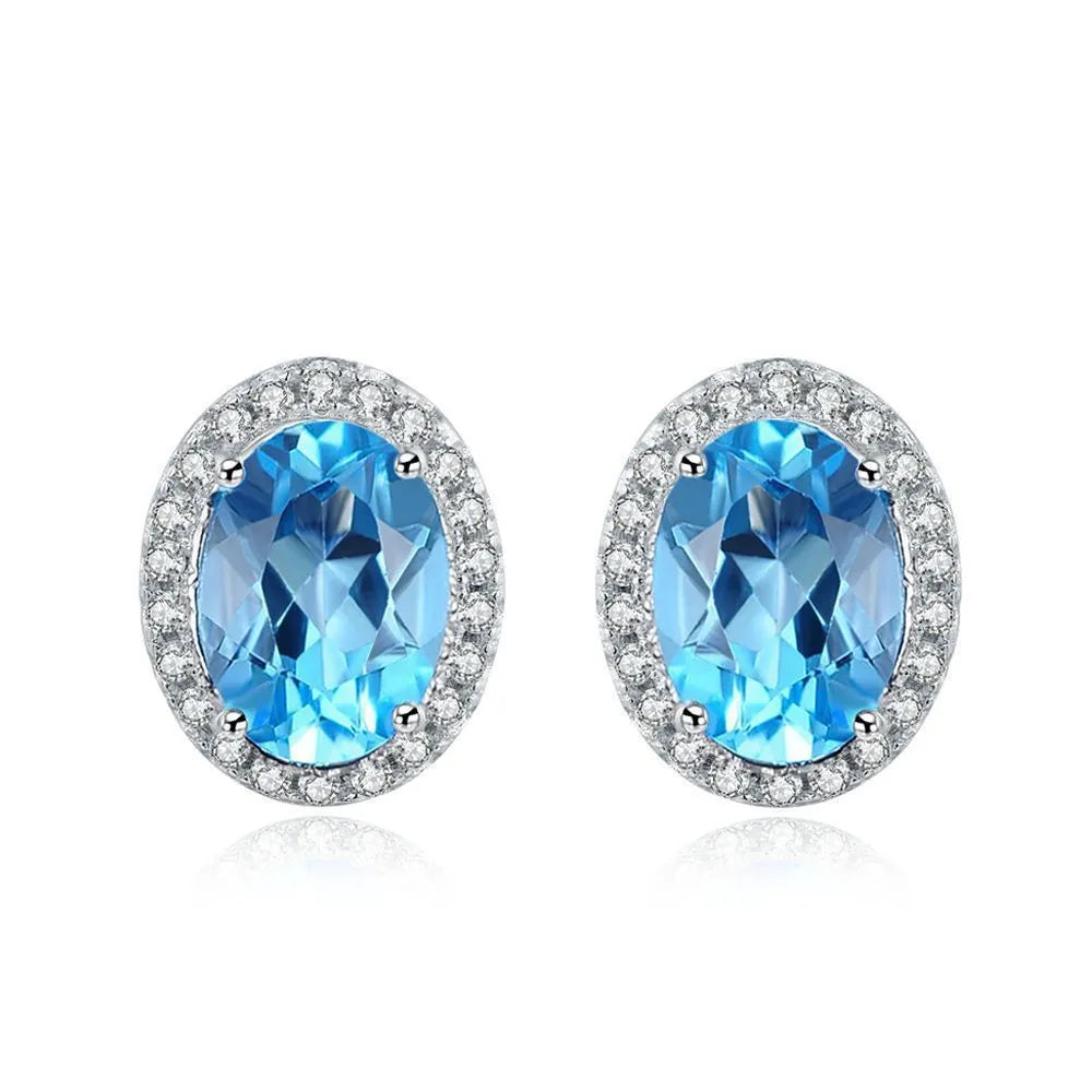 Women's 925 sterling silver jewellery set with blue topaz gemstones showing earrings, ring, pendant, and necklace with geometric pattern