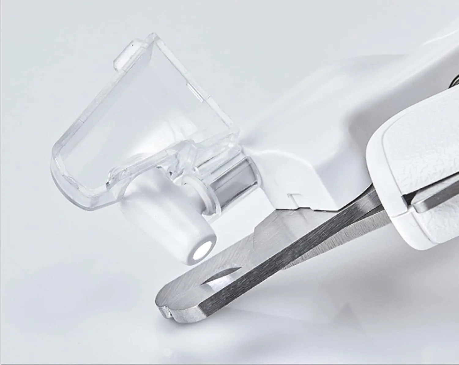 White pet nail clippers with LED light, open transparent splash guard, and separate nail file on a table