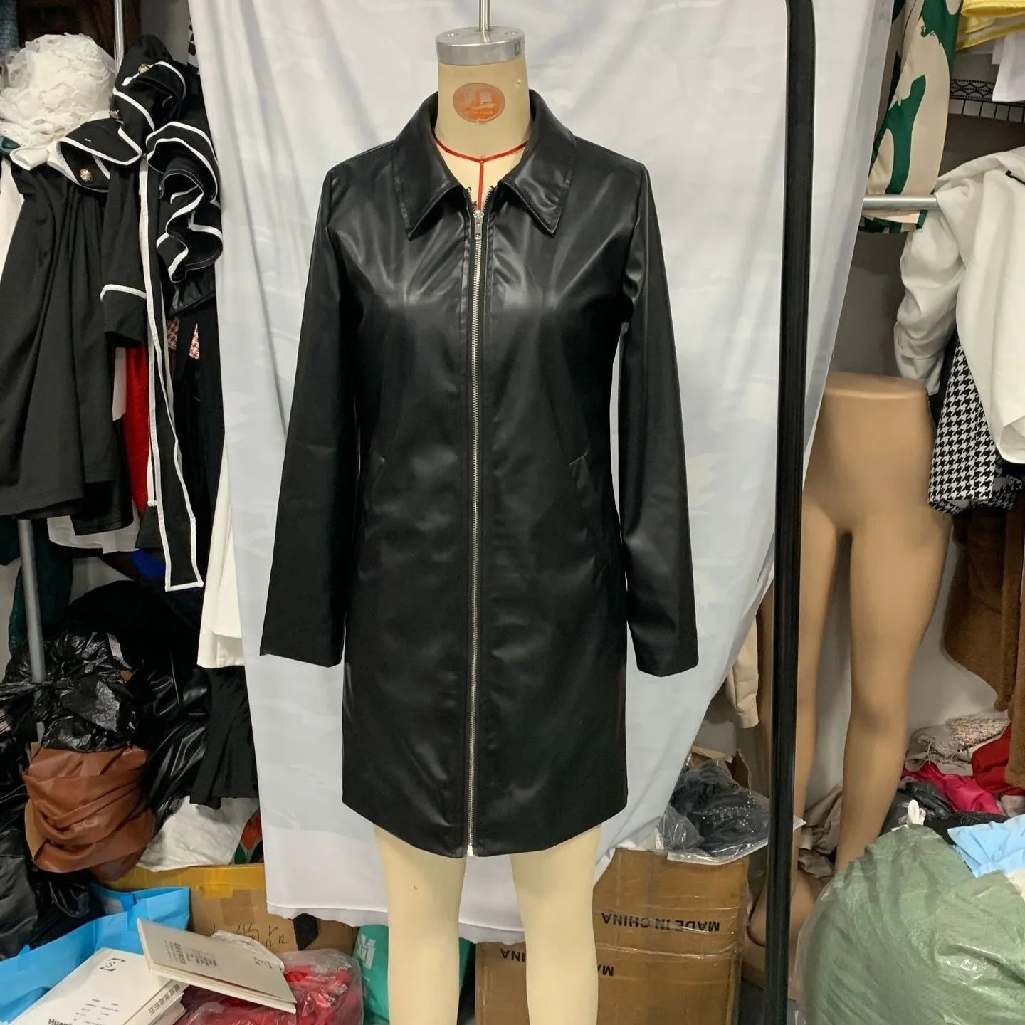 Black women's polyester leather jacket on a hanger, showing long sleeves and medium length.