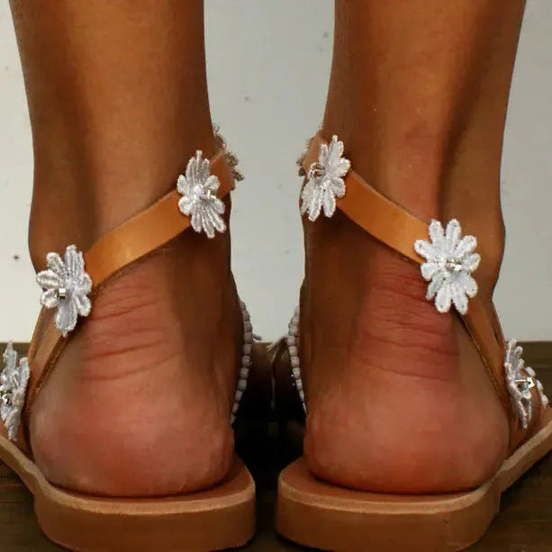 Brown women's flat Roman sandals with floral ethnic pattern and herringbone toe design on rubber sole.