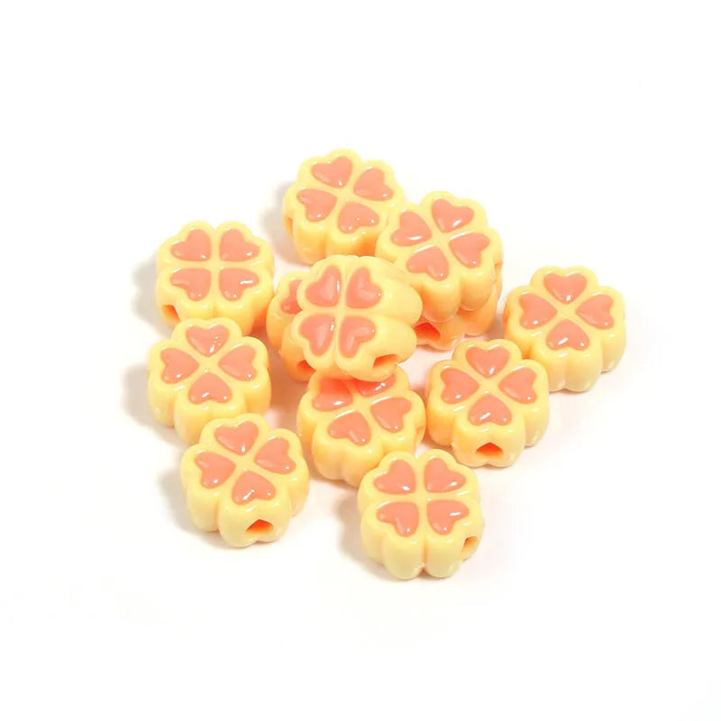 A pile of 15mm frosted acrylic four-leaf clover beads in mixed colours including pink, green, and blue.