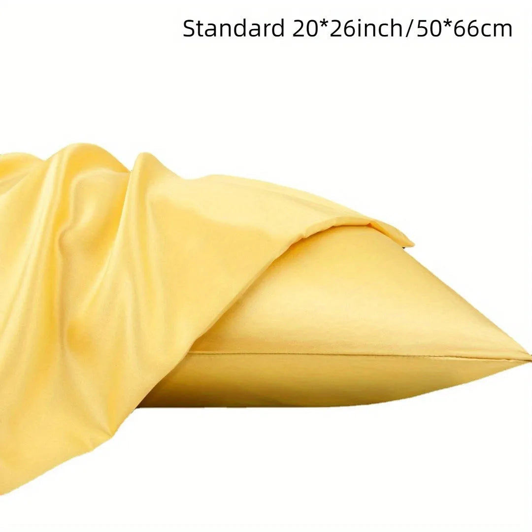 Pair of solid colour satin pillowcases in polyester fabric on a bed.