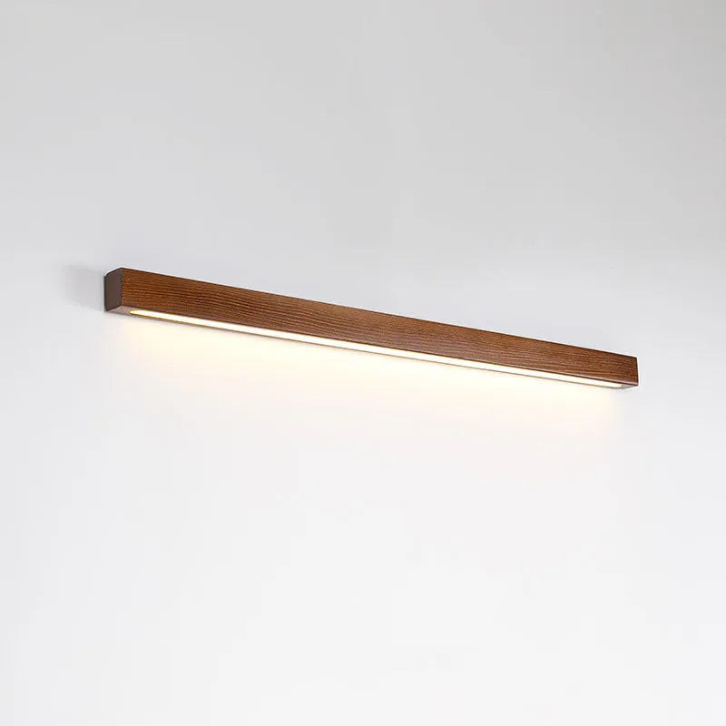 Walnut coloured log strip wall lamp with a square wood and acrylic profile mounted on a wall.