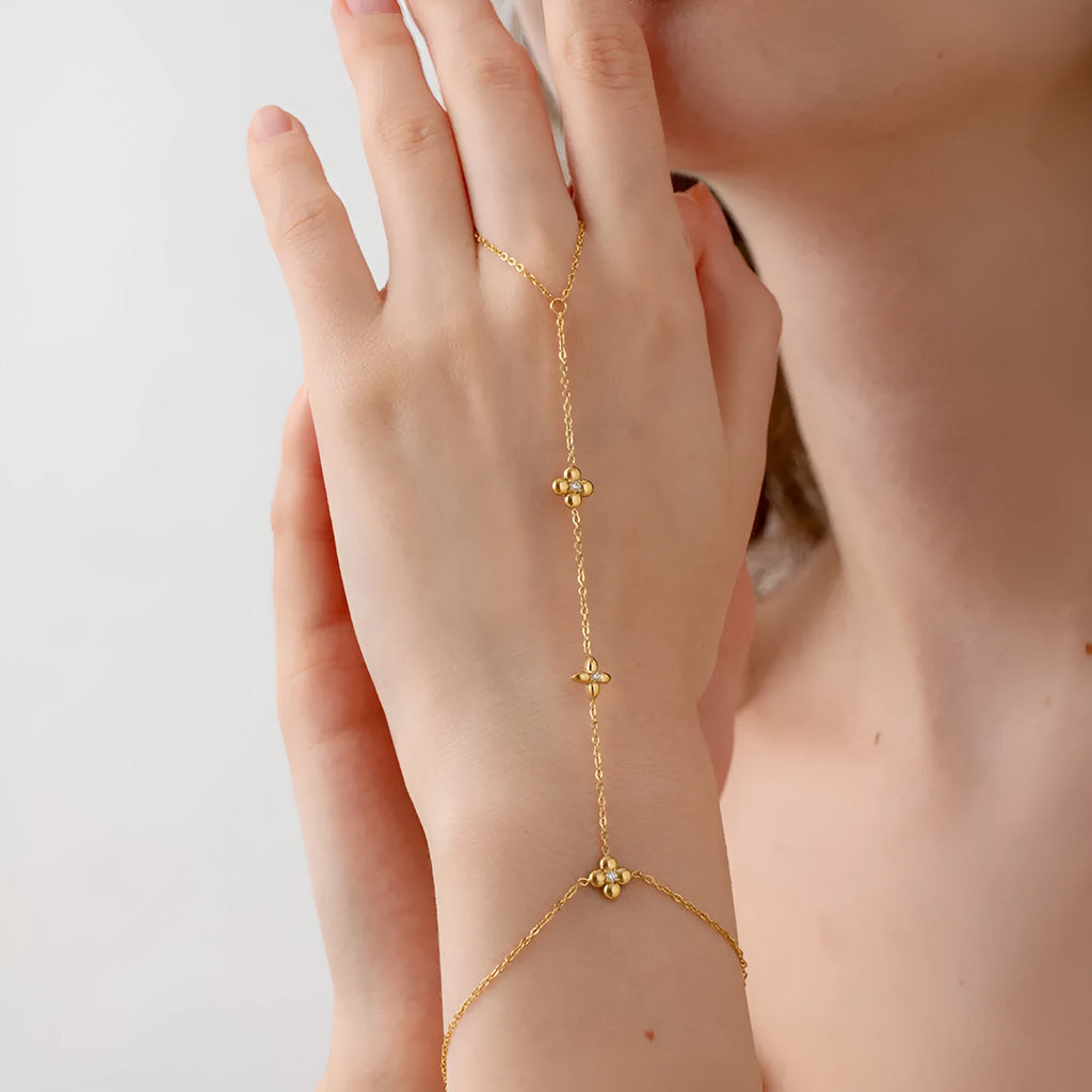 Gold stainless steel women's bracelet with geometric shape, flower and eight-pointed star details.