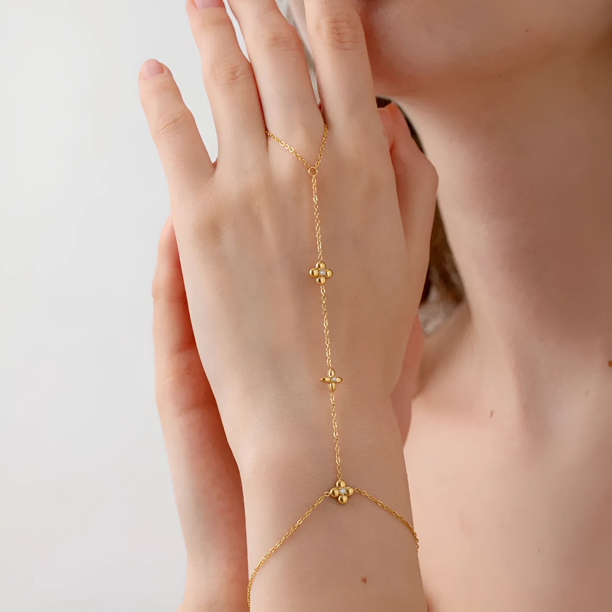 Gold stainless steel women's bracelet with geometric shape, flower and eight-pointed star details.