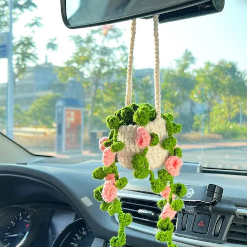 Green and white knitted wool car plant decoration with white hanging rope.