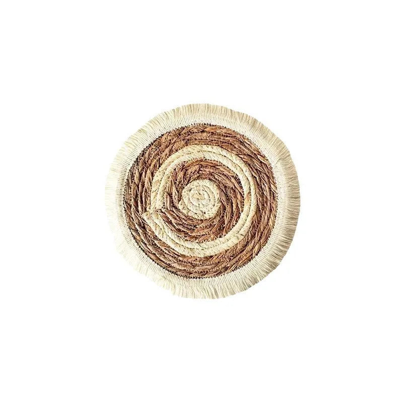 Round natural papyrus placemat with corn rope tassel trim on a wooden table.