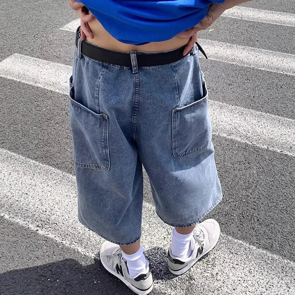 Blue washed denim shorts for men with high waist and cropped pirate-style legs on a plain background.