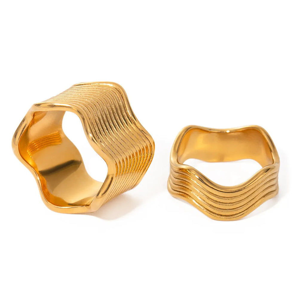 A women's stainless steel ring with a wide, sculptural geometric wave design and an electroplated silver-toned finish.