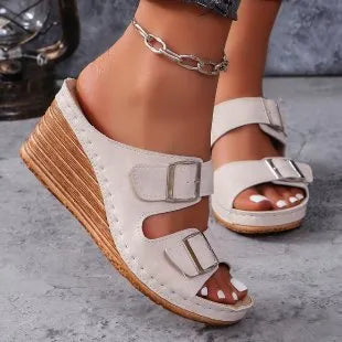 Women's creamy-white beach slippers with an outer wedge belt buckle on a flat rubber sole.