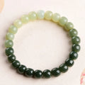 Natural Hetian jade bracelet with gradient clear water coloured beads on a wrist.