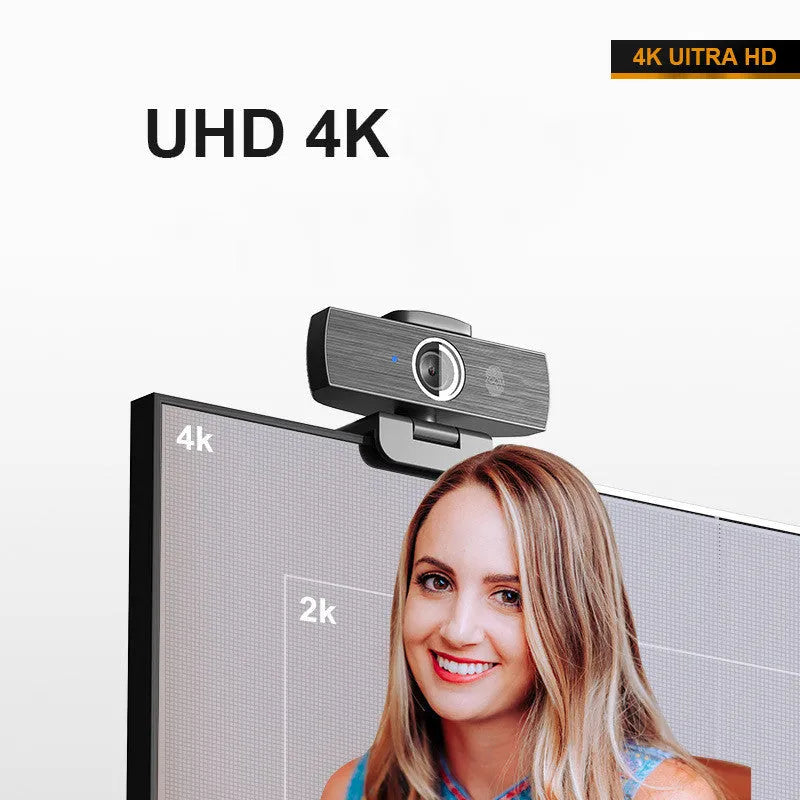 Black USB webcam with magnetic privacy cover on a desk next to a laptop