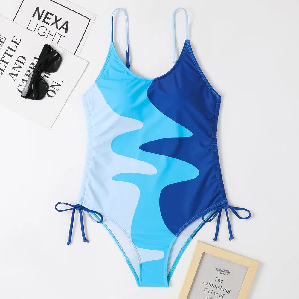 Women's sleeveless backless one-piece swimsuit in a striped pattern, shown in blue.