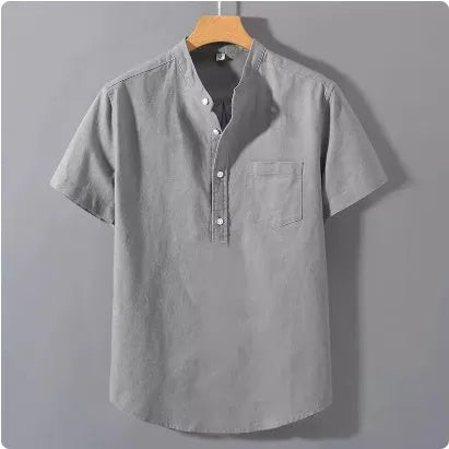 Man wearing a beige loose-fit linen shirt with a stand collar and short sleeves.
