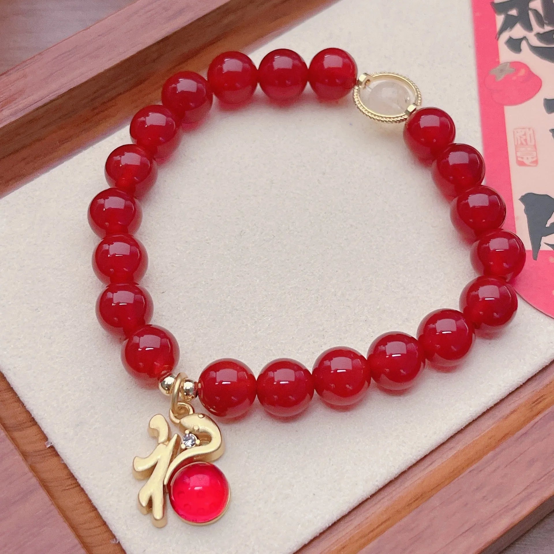A red agate bracelet for women with Chinese style dragon and lucky bag motifs.