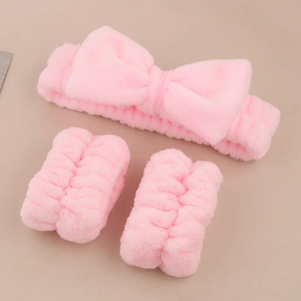 Keep dry facial brush set with plastic handle, coral fleece hair band, and stack of purple and pink face wash sponge suits.