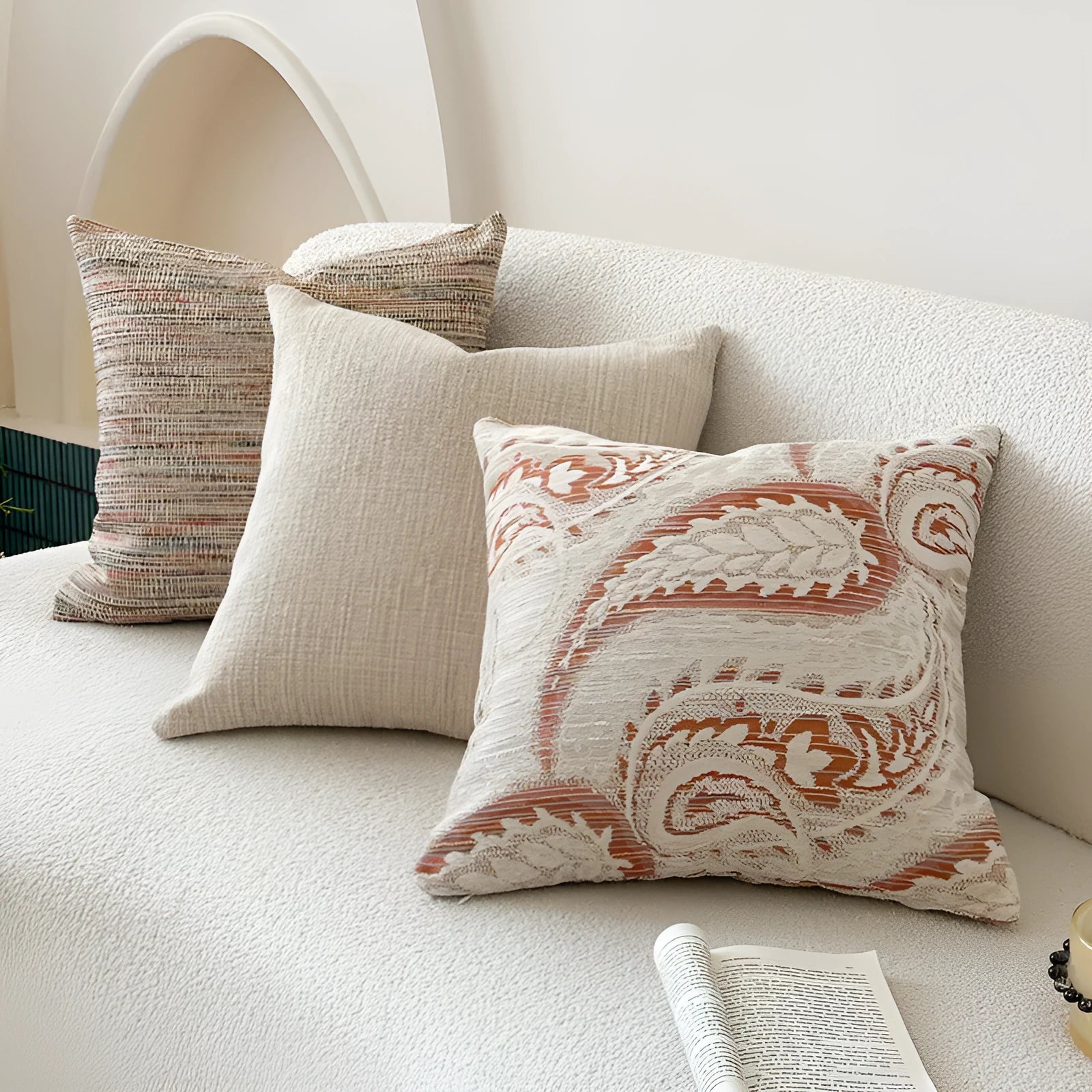 Amber coloured jacquard pillow cover with paisley and floral pattern, shown on a sofa.