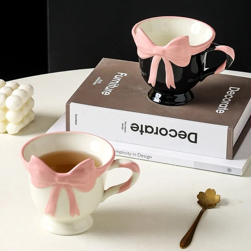 Ceramic mug with a pink and white girl's heart bow decoration on the side.