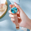 Women's rose shell alloy case watch with mesh strap, showing dial colour options: white, black, blue, red, pink, green.